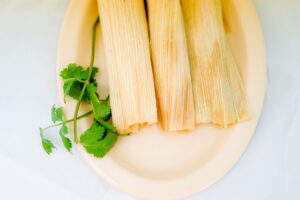 Tamales on a plate with a parsley garnish.